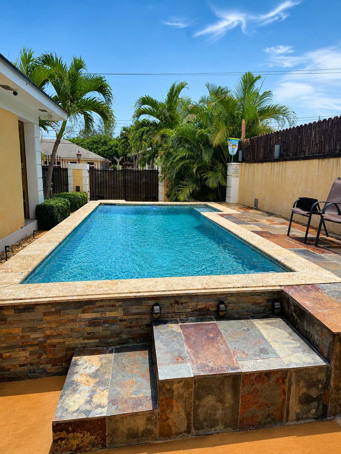 Raised stone-edged pool under palms on a sunny day