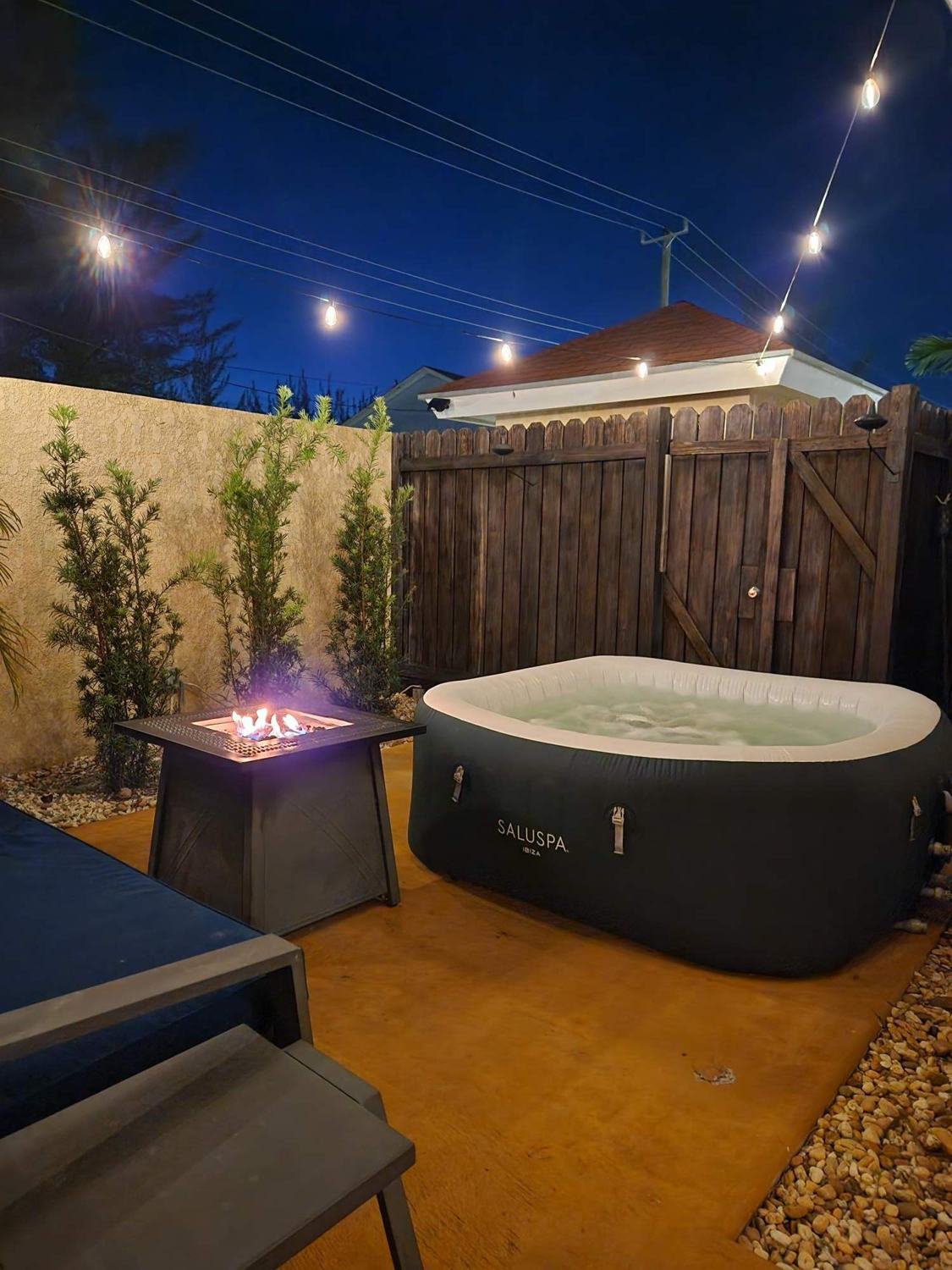 Jacuzzi and fire table at night under string lights